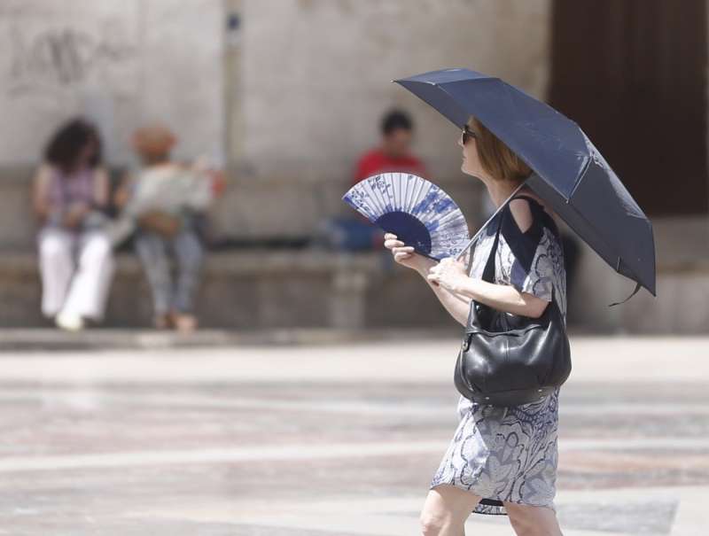 Una mujer se abanica y se protege del sol con un paraguas.EFE/ Kai Forsterling/Archivo
