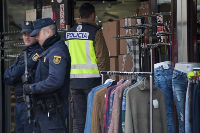 Agentes de policía entran en una tienda para verificar la veracidad de las marcas de ropa del establecimiento. /EFE