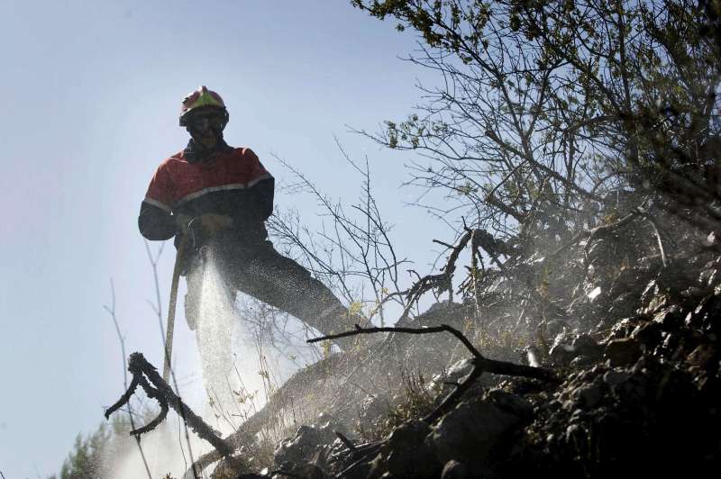 Un bombero refresca una zona arrasada por un incendio forestal. EFERubn FrancsArchivo