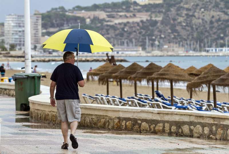 Una persona pasea por una playa de Alicante en un día de lluvia.