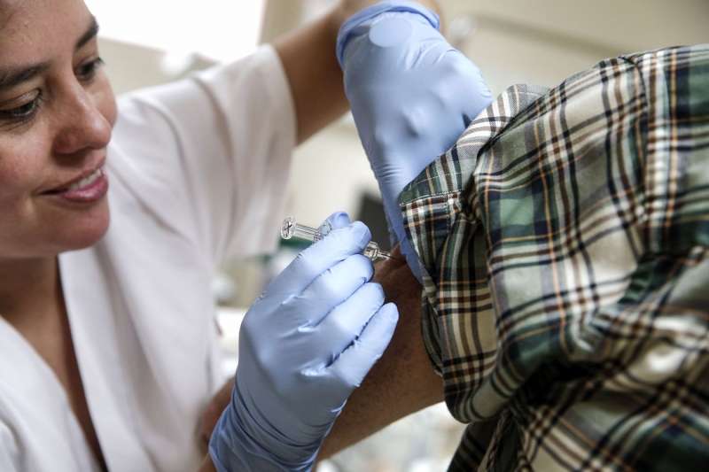 Una enfermera coloca una dosis de la vacuna de la gripe a una paciente. EFE/Manuel Bruque/Archivo
