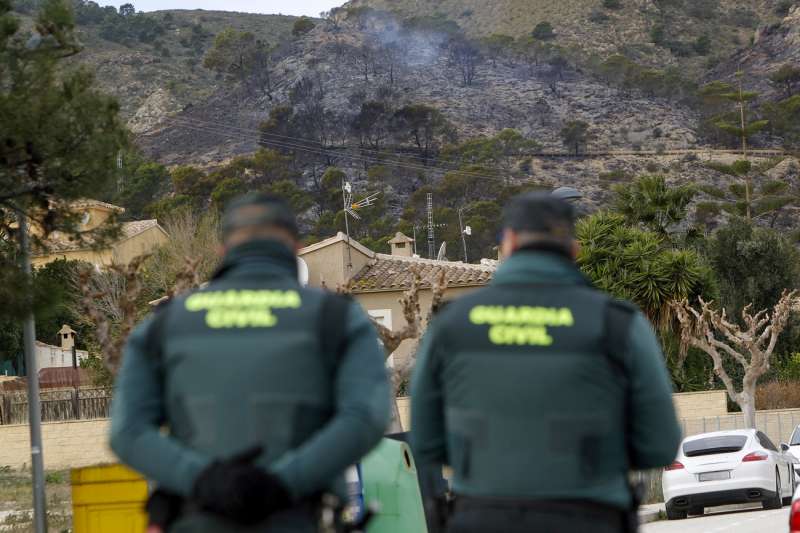 Dos agentes de la Guardia Civil contemplan el paraje afectado por el incendio en la parte trasera del Cabesot, en el término municipal de Aigües (Alicante). EFE/Morell
