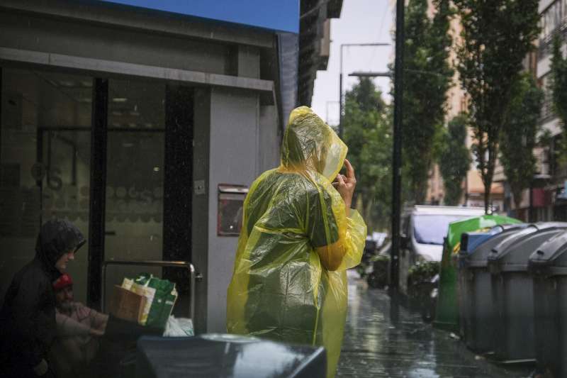 Una persona se protege de la intensa lluvia este viernes en Alicante. EFE  Pablo Miranzo