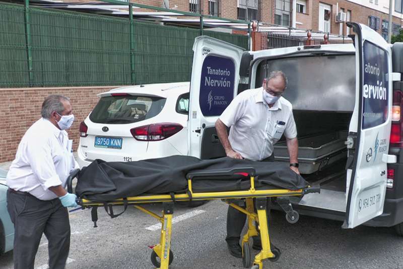  Operarios de una funeraria trasladan el cuerpo de una mujer encontrada muerta en su casa./ EFE