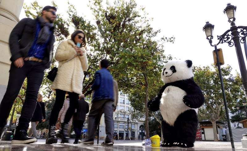  Varias personas pasean ante un hombre disfrazado de oso panda. /EFE