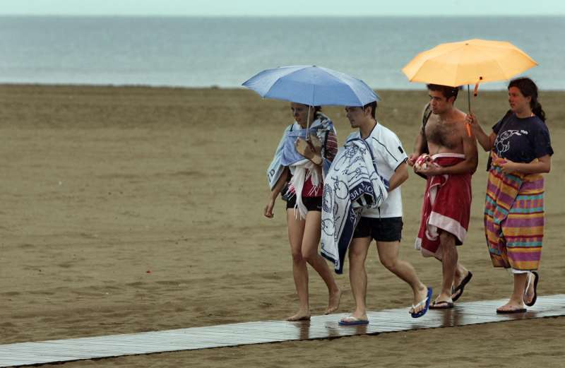 Imagen de archivo de varios jÃ³venes resguardÃ¡ndose de la lluvia en la playa de la Malvarrosa de Valencia. / EFE